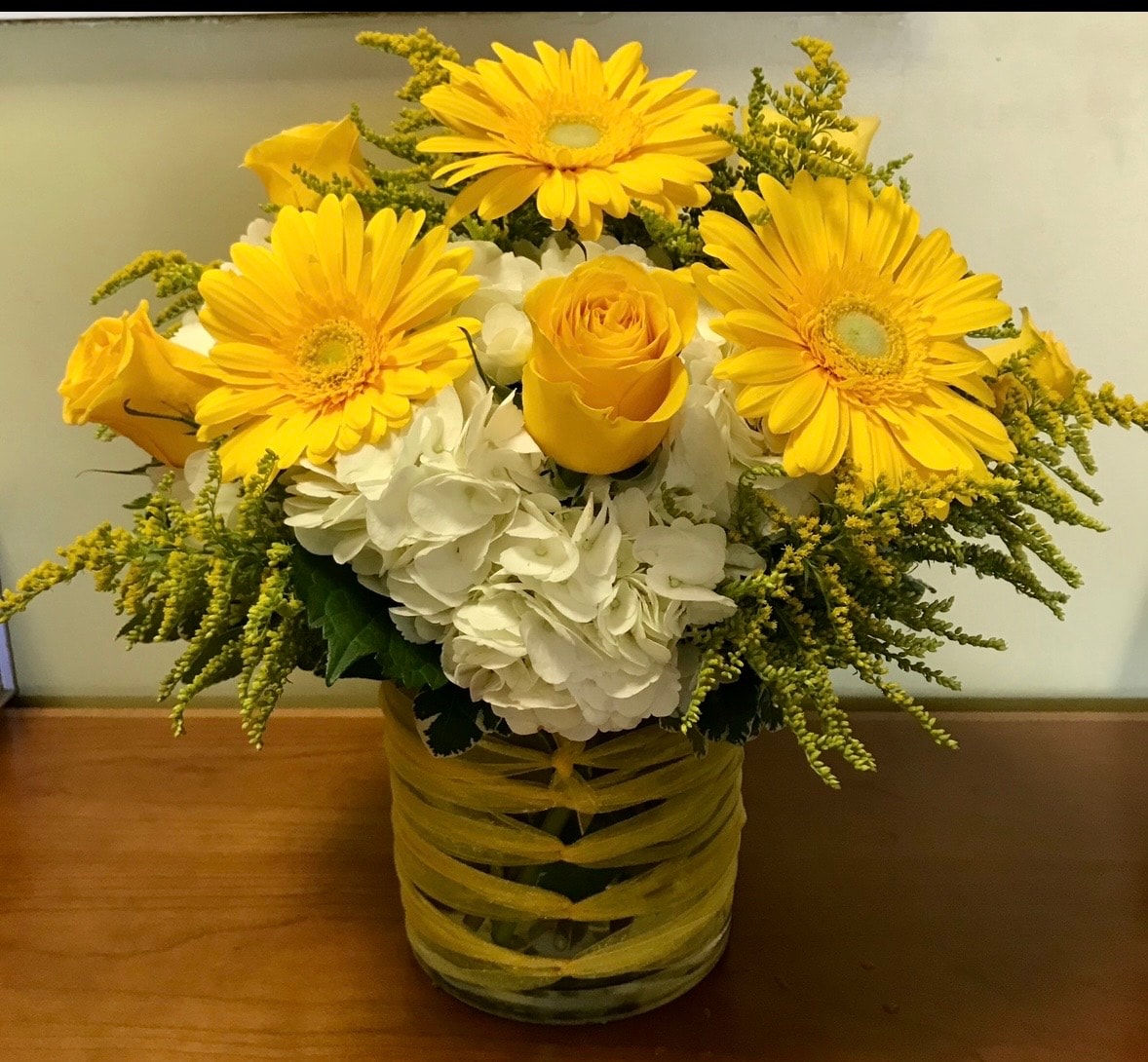 Everyday floral arrangement with yellow gerbera daisies, yellow roses and white hydrangeas in ribbon-wrapped vase